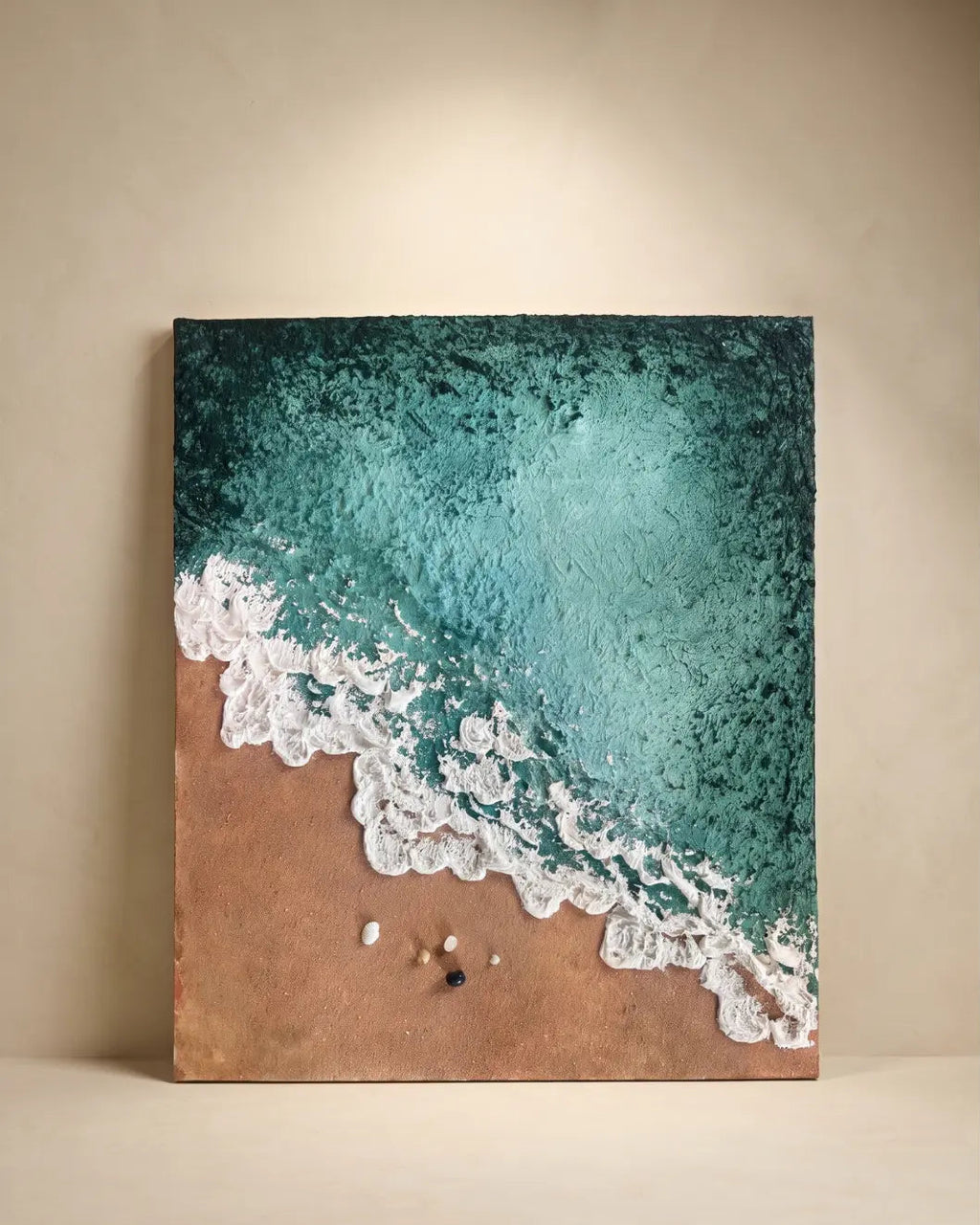 A square canvas wall art print depicting an aerial view of turquoise ocean waves washing onto a sandy beach, displayed against a neutral beige wall.