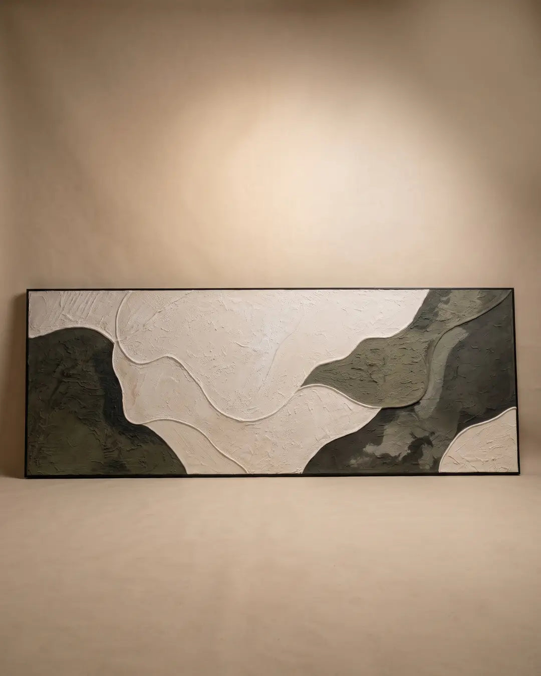 A rectangular framed wall art piece with an abstract wavy design in off-white, charcoal gray, and dark olive green, displayed against a warm beige wall with a spotlight above.