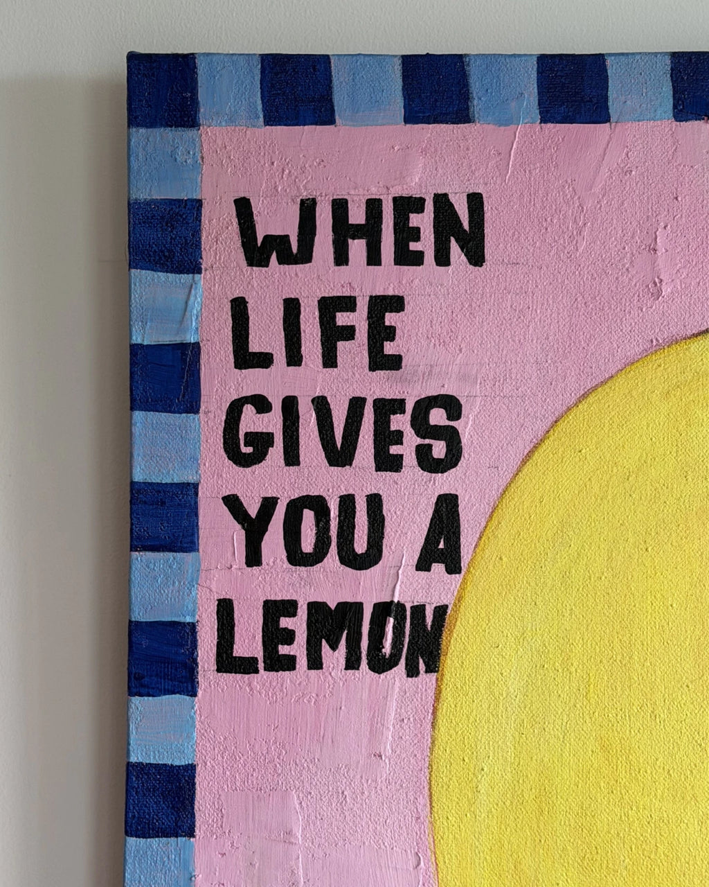 Artistic wall decor with 'When Life Gives You a Lemon' text on a pink background with blue and yellow accents.