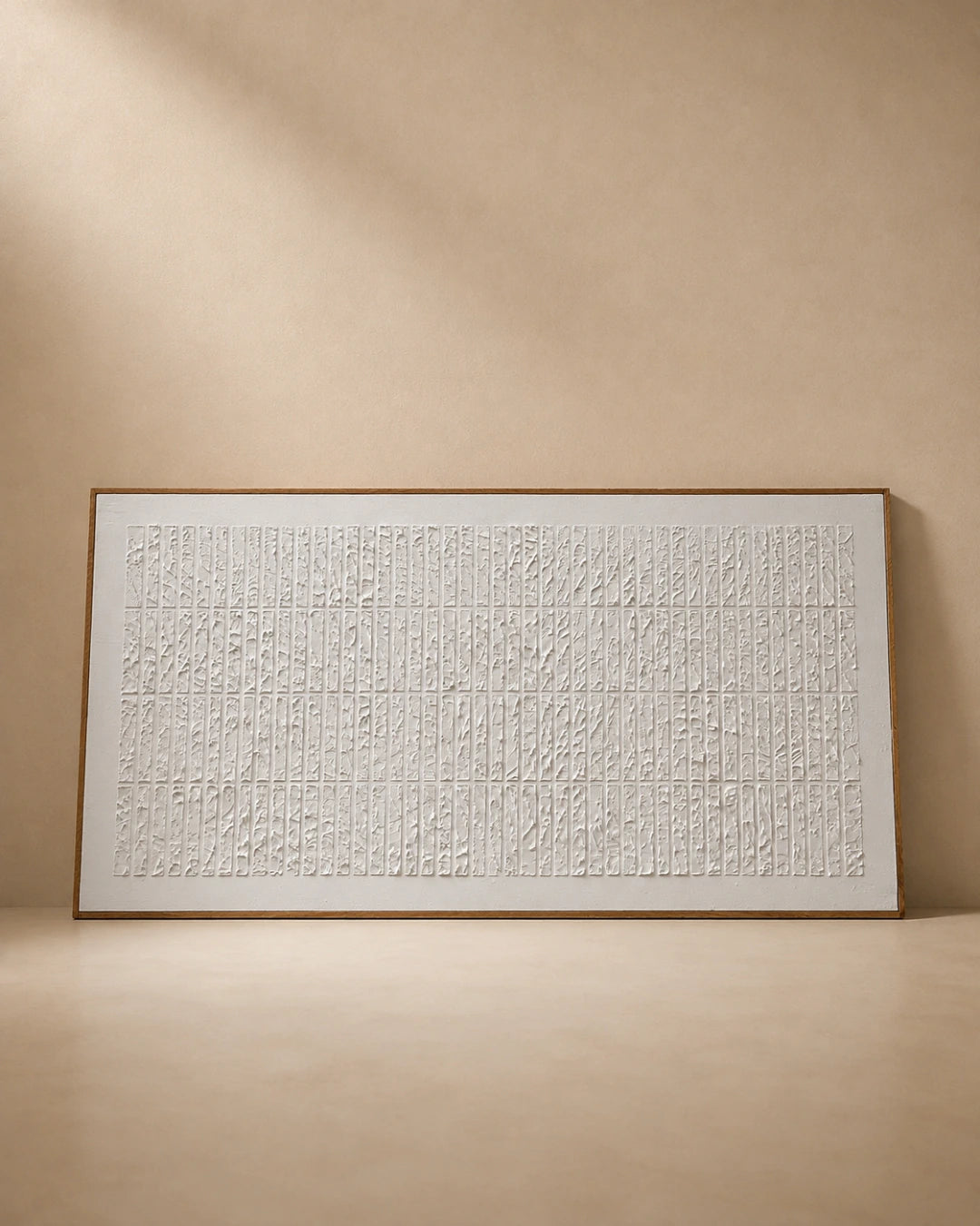 A large framed abstract wall art piece with a white textured surface and dense vertical line pattern, set against a warm beige wall and floor.