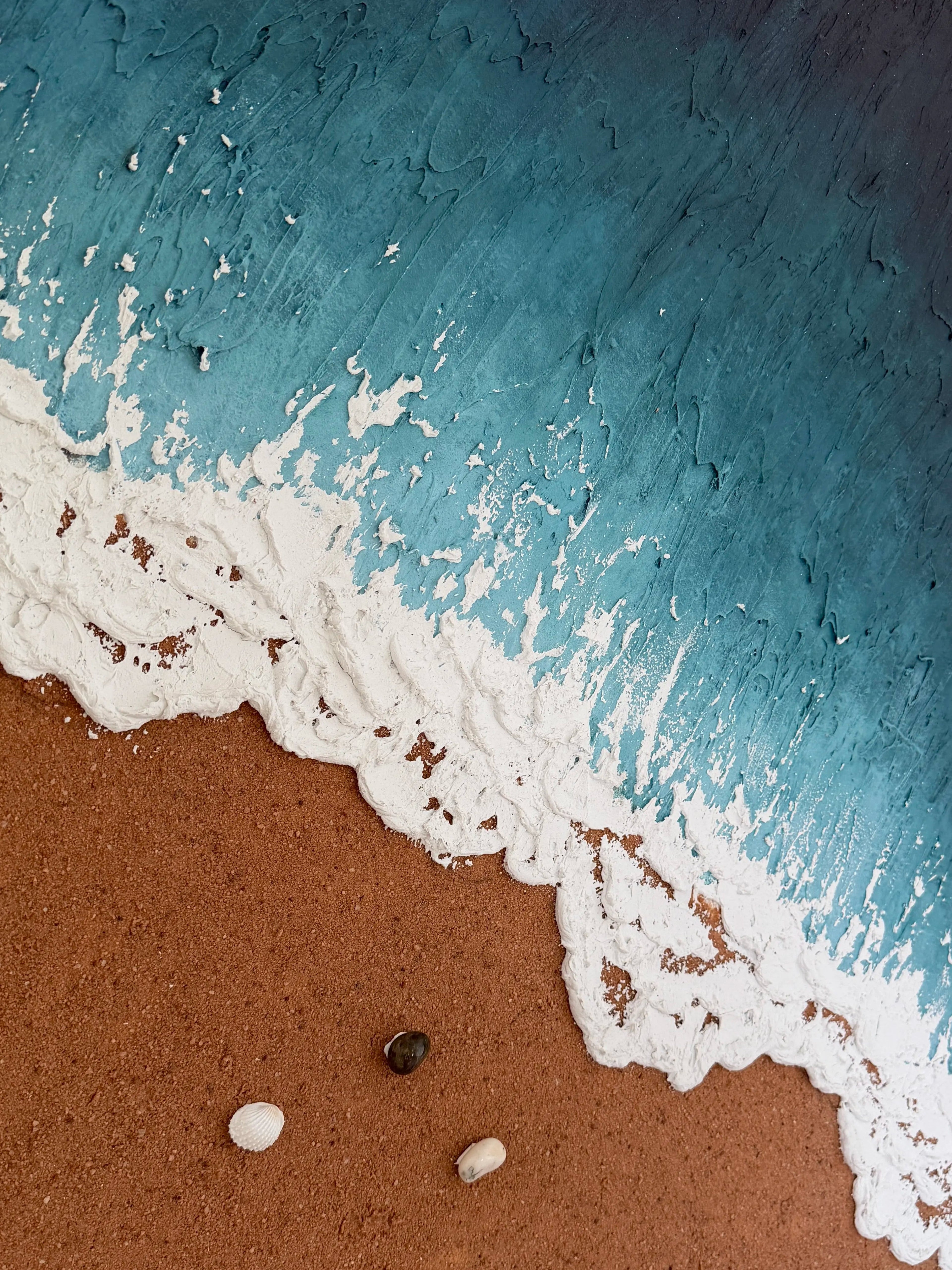 Close view of handmade beach wall art with turquoise water, sculpted white waves, sandy texture, and natural seashell accents.
