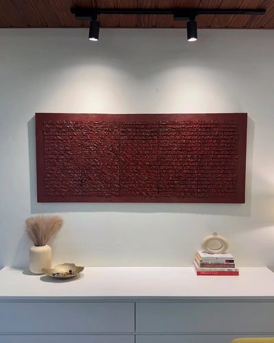 Brickwork deep red textured painting hanging above a console table with books and vases