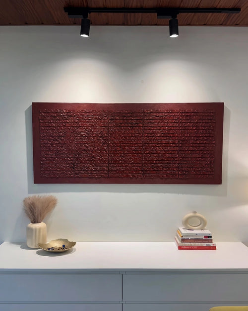Brickwork deep red textured painting hanging above a console table with books and vases