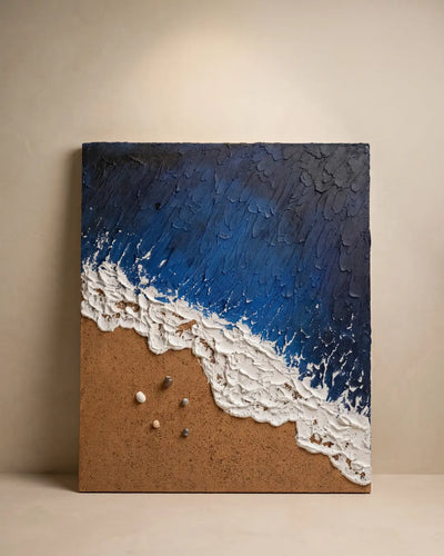 A square canvas wall art piece depicting a textured ocean wave with deep blue water, white foam, and a sandy brown shore, displayed against a neutral beige wall.