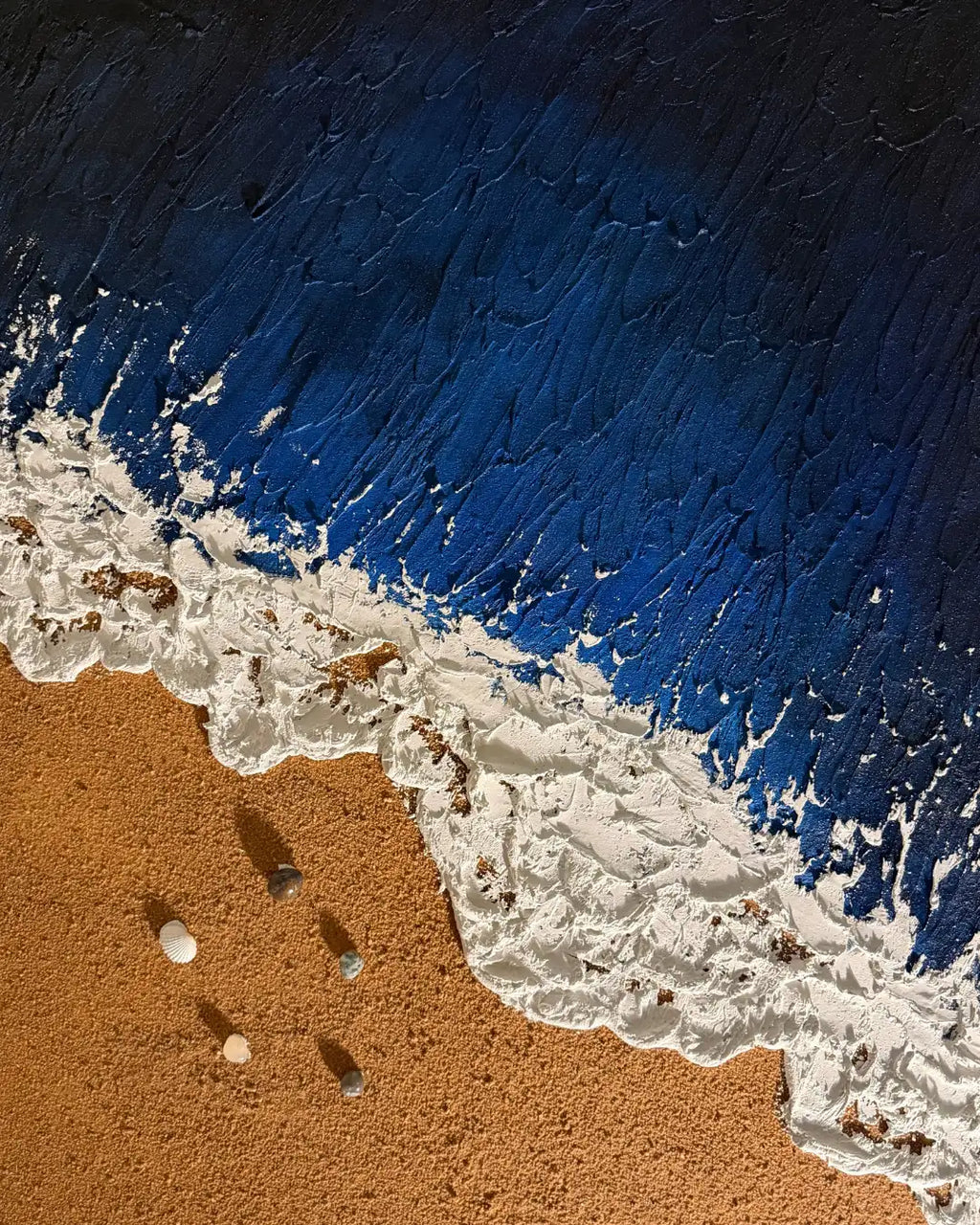 Close view of handmade ocean wall art with layered blue textures, sculpted white surf, and sandy shoreline details.