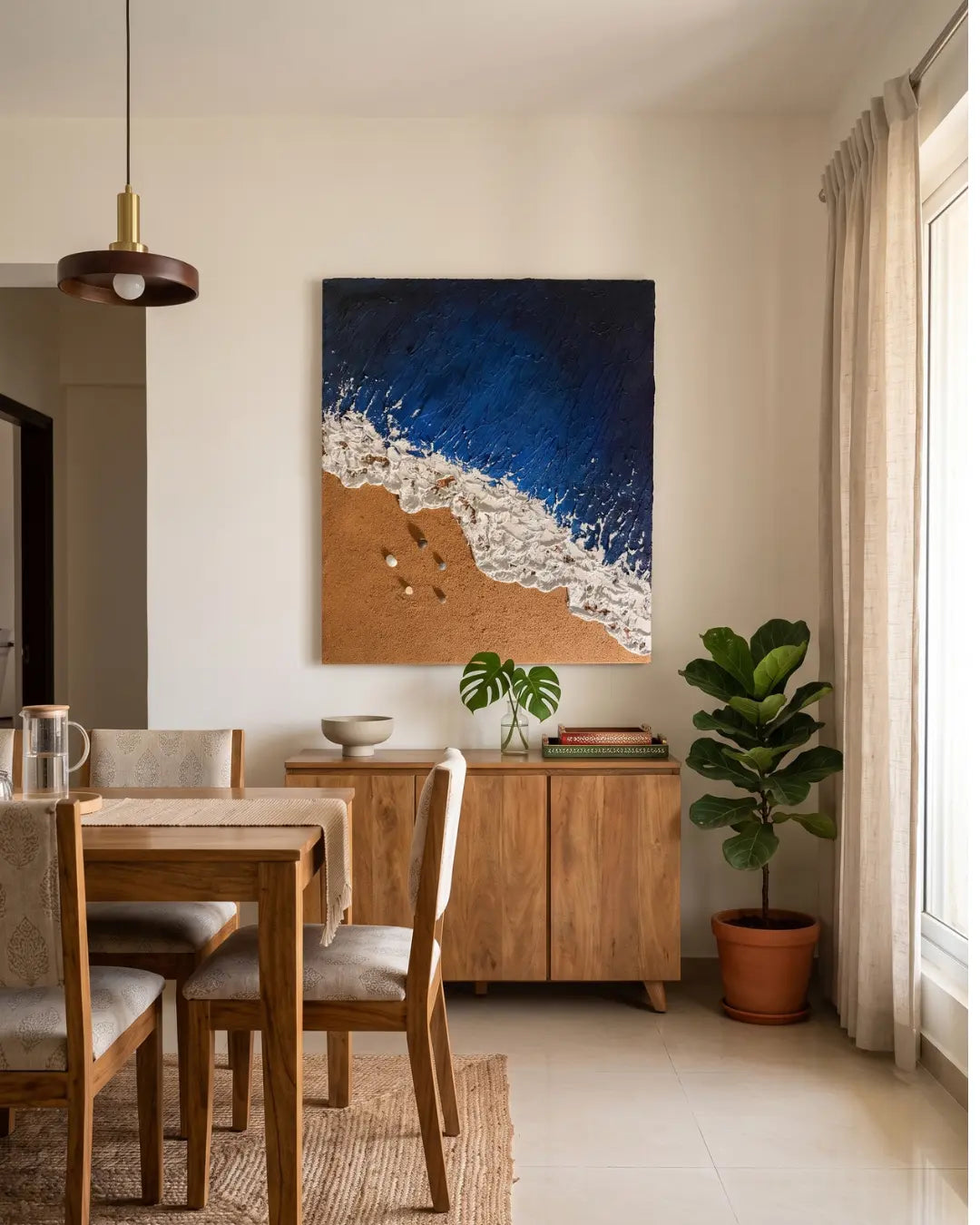 Handmade coastal wall art featuring rich blue sea textures and foamy surf styled above a contemporary wooden dining console.
