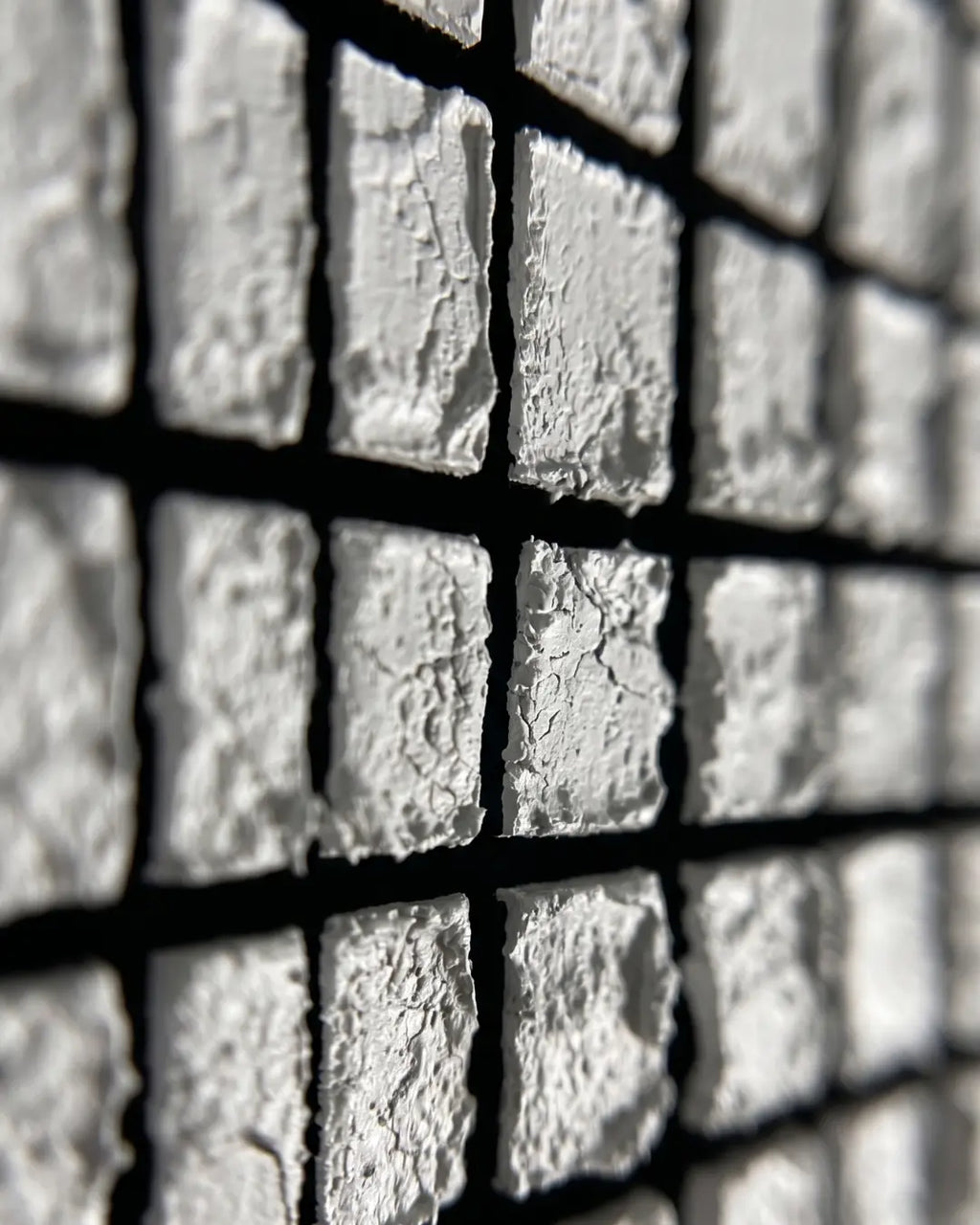 Close-up of hand-pressed white tiles on Mosaic canvas showing rough individual edges and black seams
