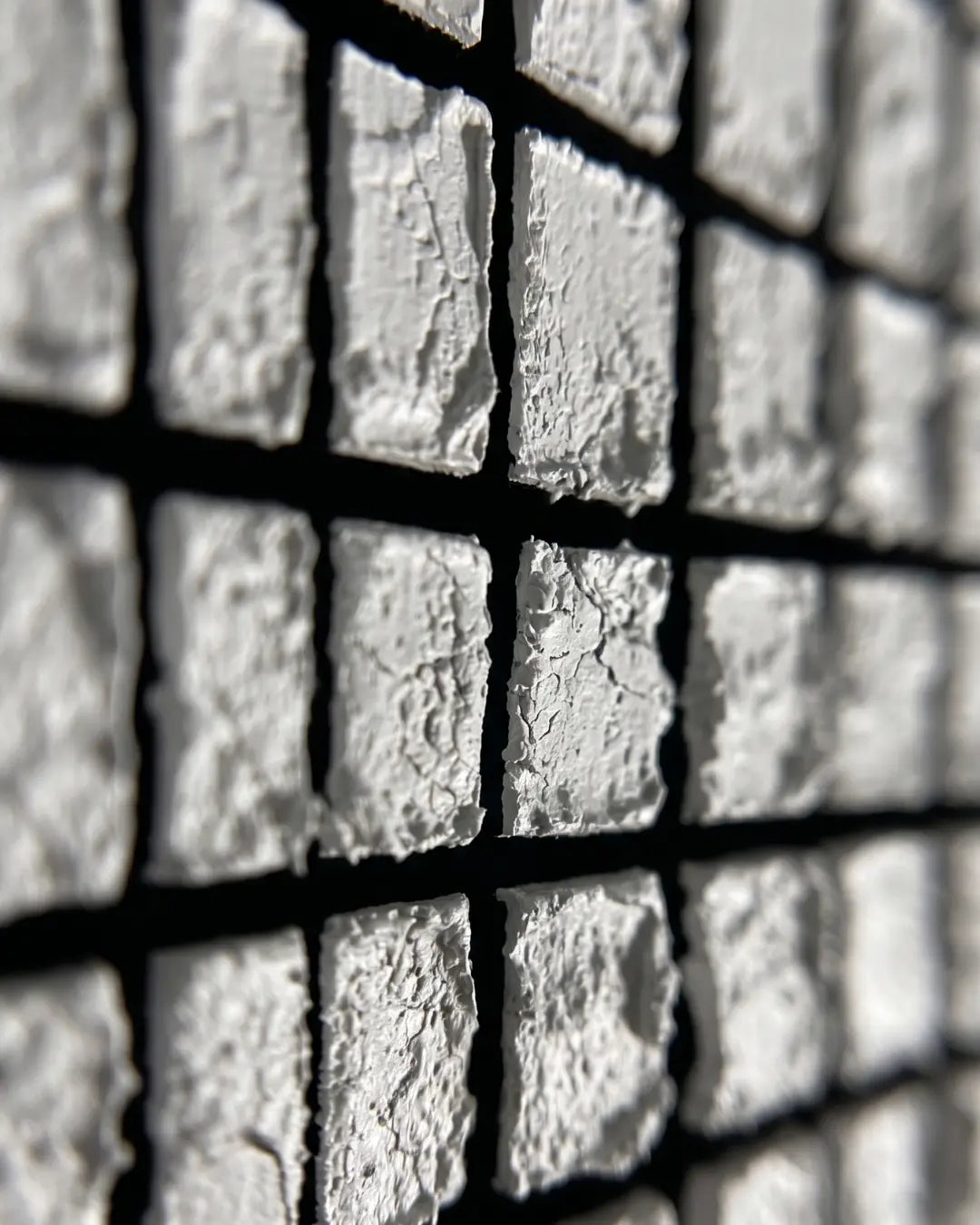 Close-up of hand-pressed white tiles on Mosaic canvas showing rough individual edges and black seams