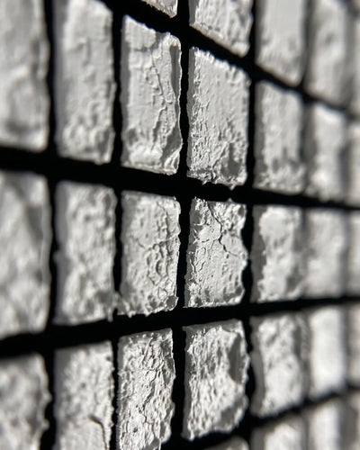 Close-up of hand-pressed white tiles on Mosaic canvas showing rough individual edges and black seams