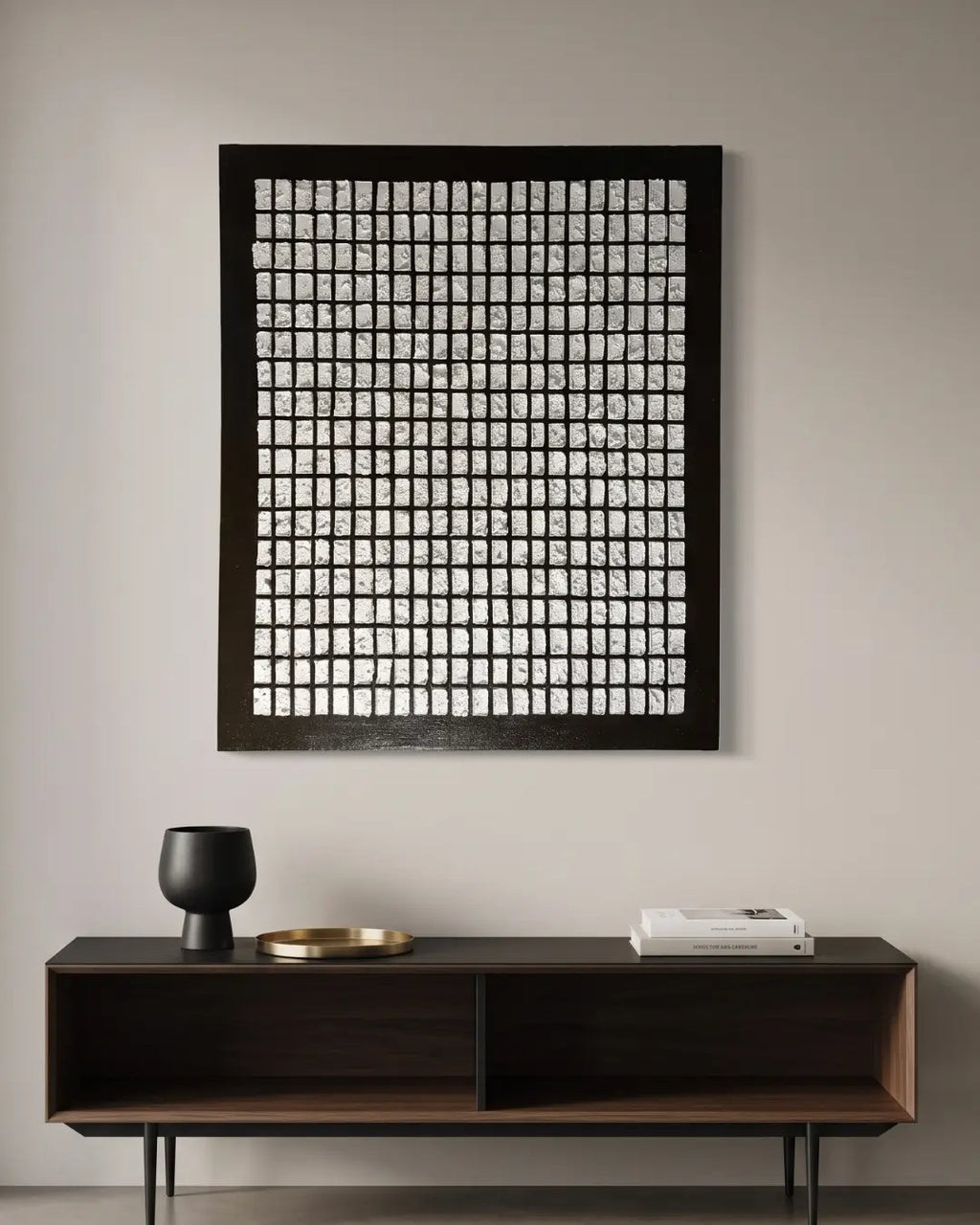 A large framed wall art piece with a black grid pattern on a white background, hanging on a light gray wall above a dark wood console table with decorative objects.